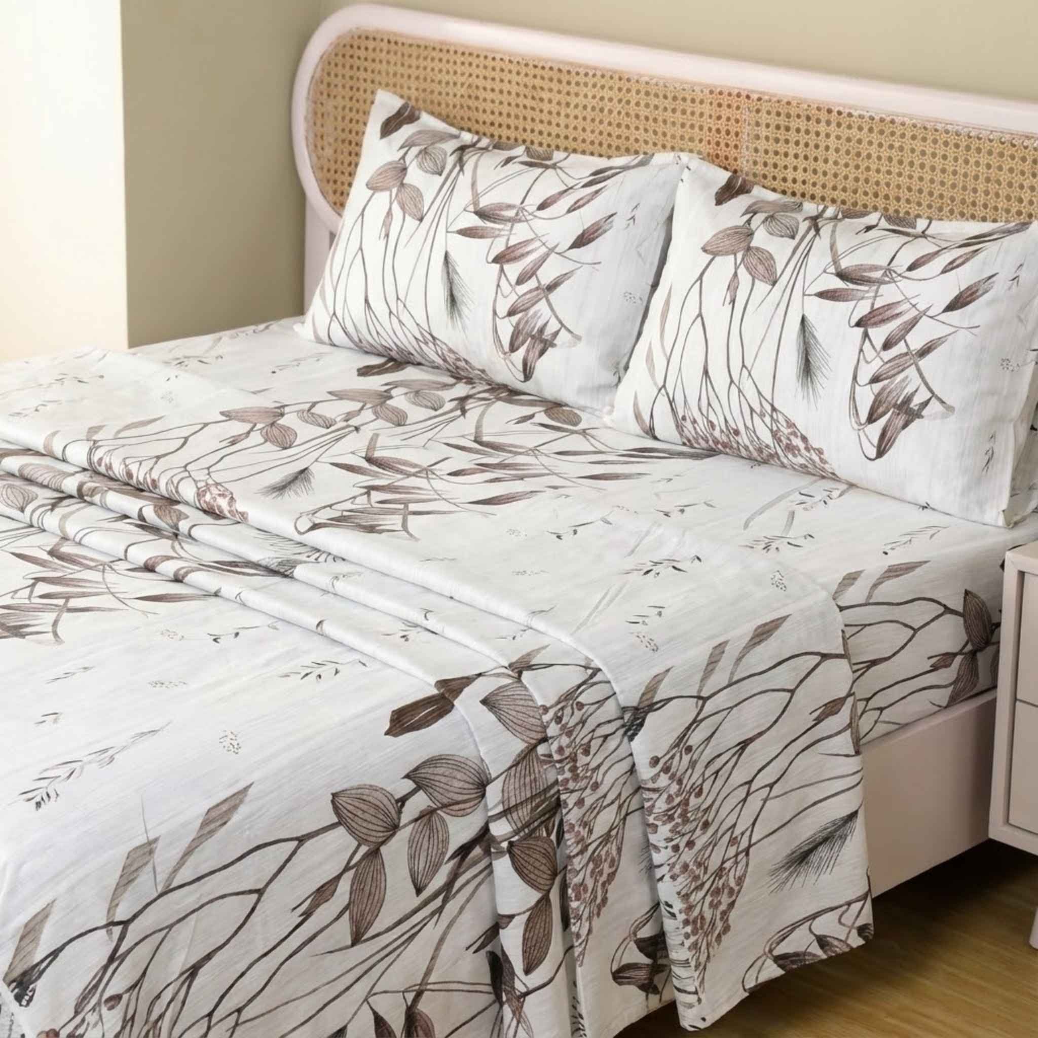 Bed with floral-patterned bedding and pillows against a beige wall.