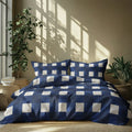 Blue and white checkered bedding set on a bed with plants and sunlight in the background
