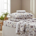Floral bedding set on a bed with pillows and a towel in a bedroom setting.