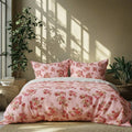 Floral bedding set on a bed with plants and sunlight casting shadows on the wall.