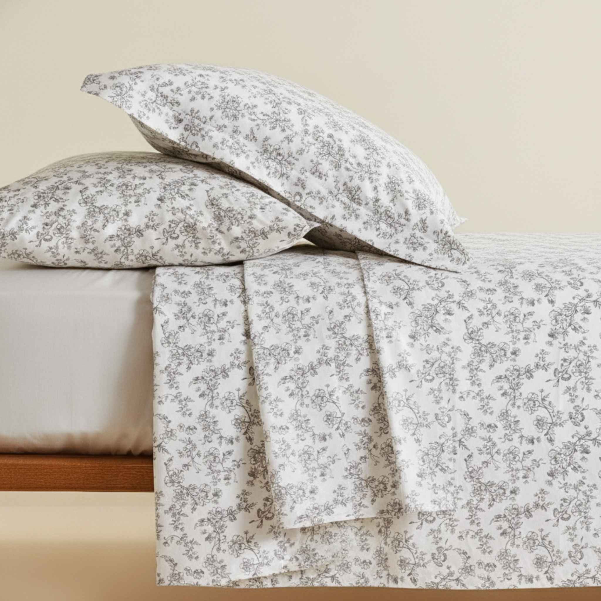 Floral patterned bed sheets and pillows on a bed with a neutral background