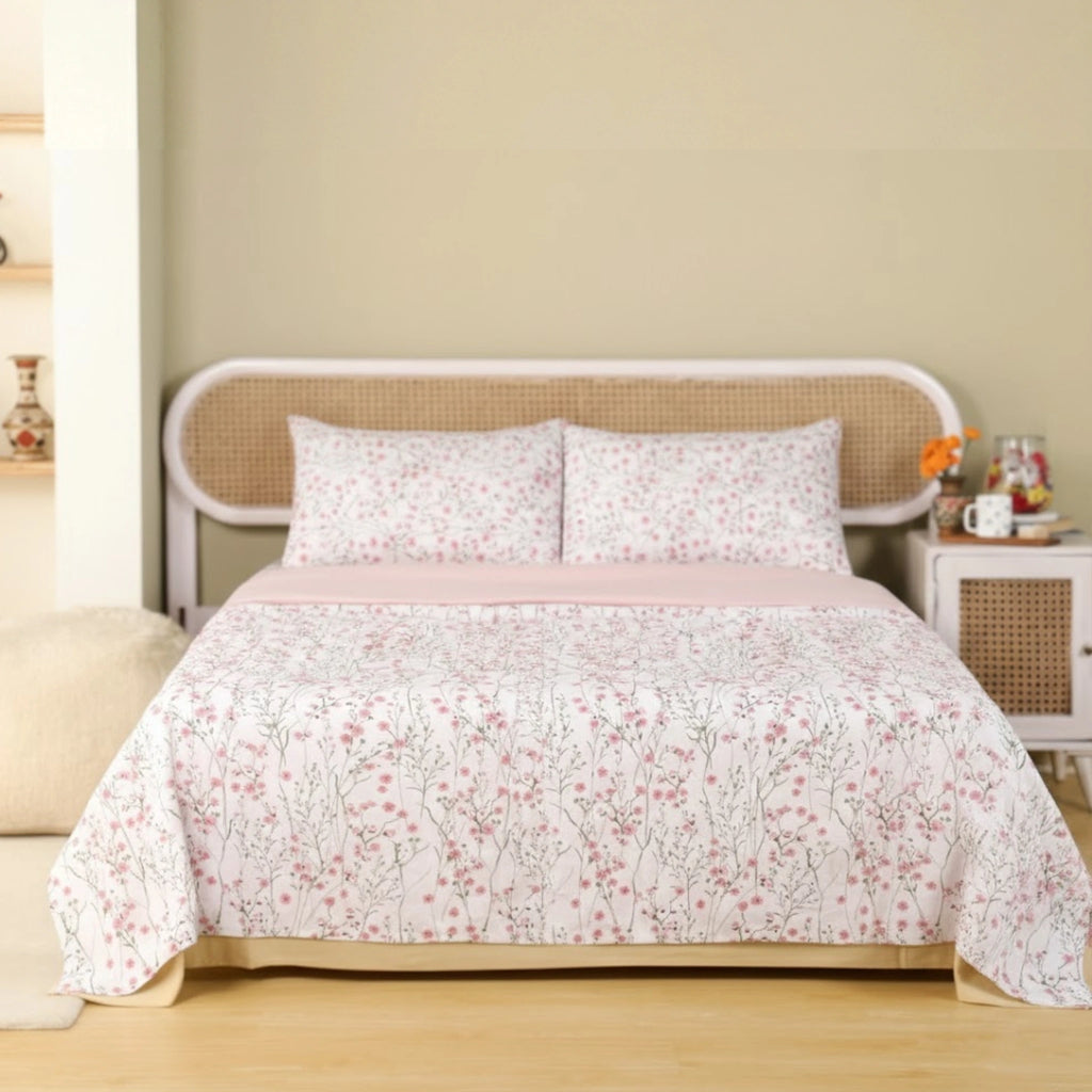 Floral patterned bedspread on a bed with a beige wall and wooden floor.