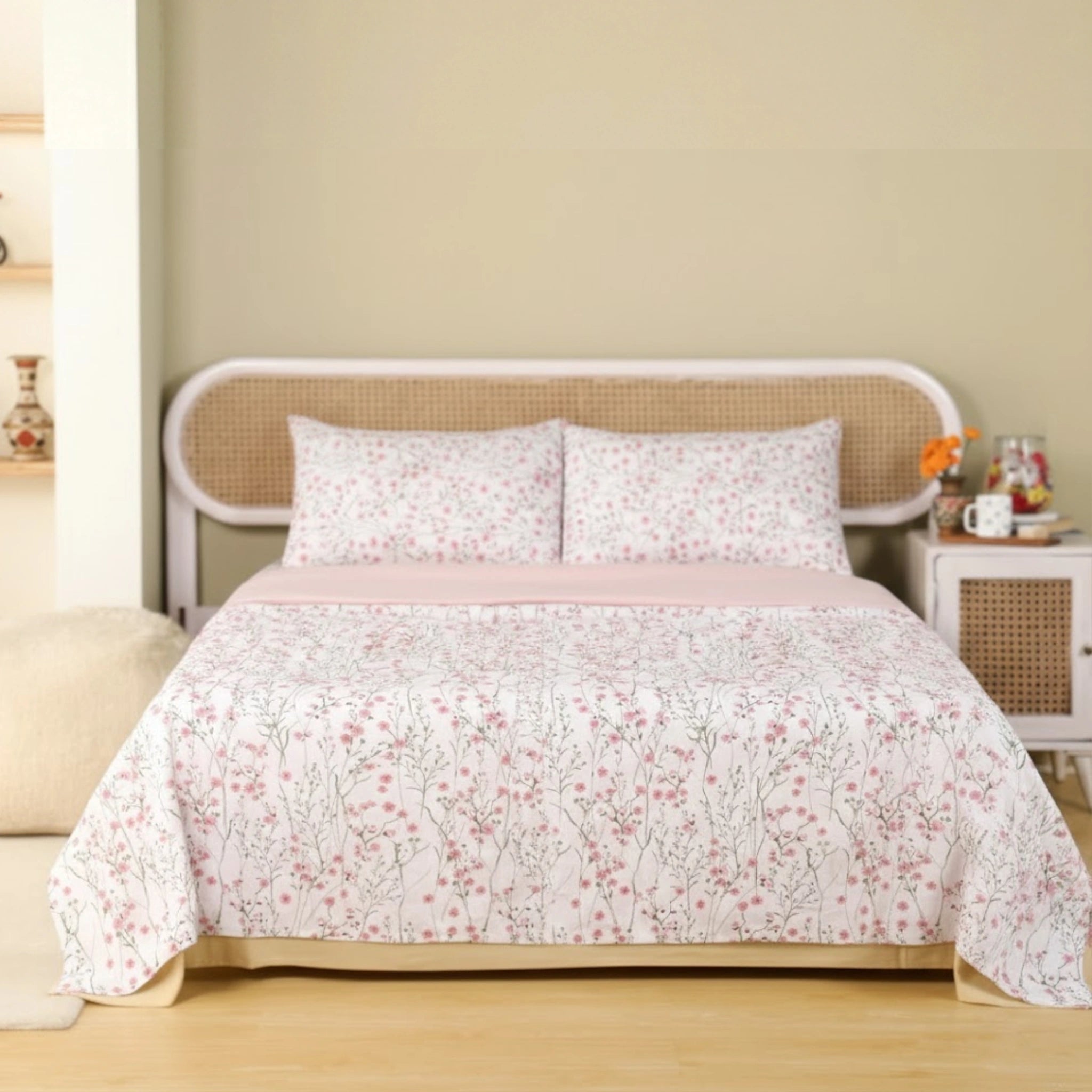 Floral patterned bedspread on a bed with a beige wall and wooden floor.