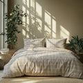 Plaid duvet cover on a bed with pillows in a room with plants and sunlight.